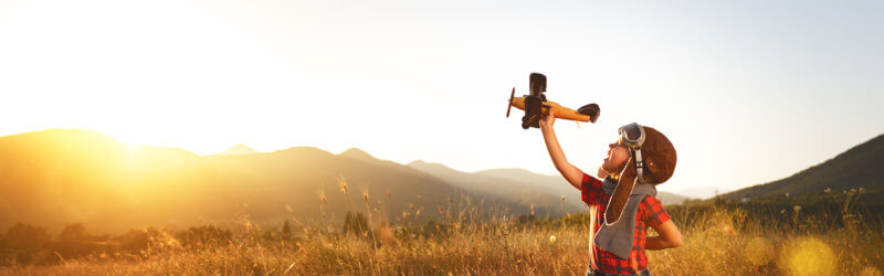 Banner - Kid playing with airplane in a open field at sunset