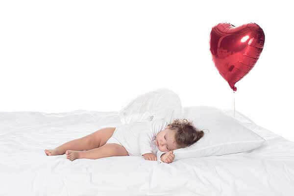 baby sleeping in a bed - heart balloon