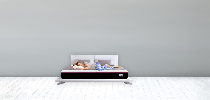 Omni Mattress Bed in a Grey Room with a lady laid on it.